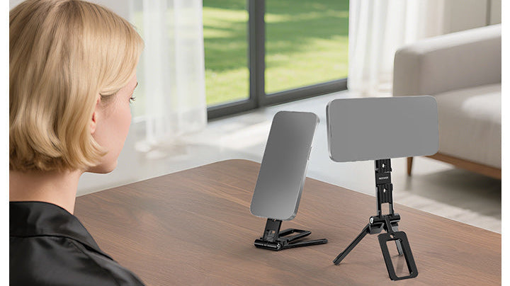 A woman looks at two smartphones mounted on magnetic phone mounts placed on a wooden table