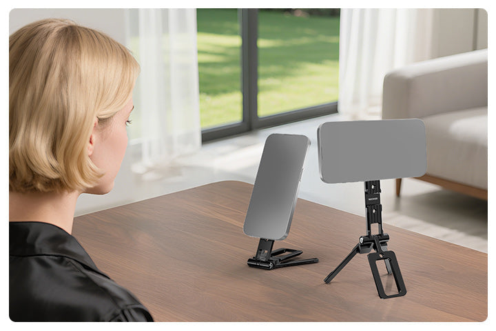 A woman looks at two smartphones mounted on magnetic phone mounts placed on a wooden table