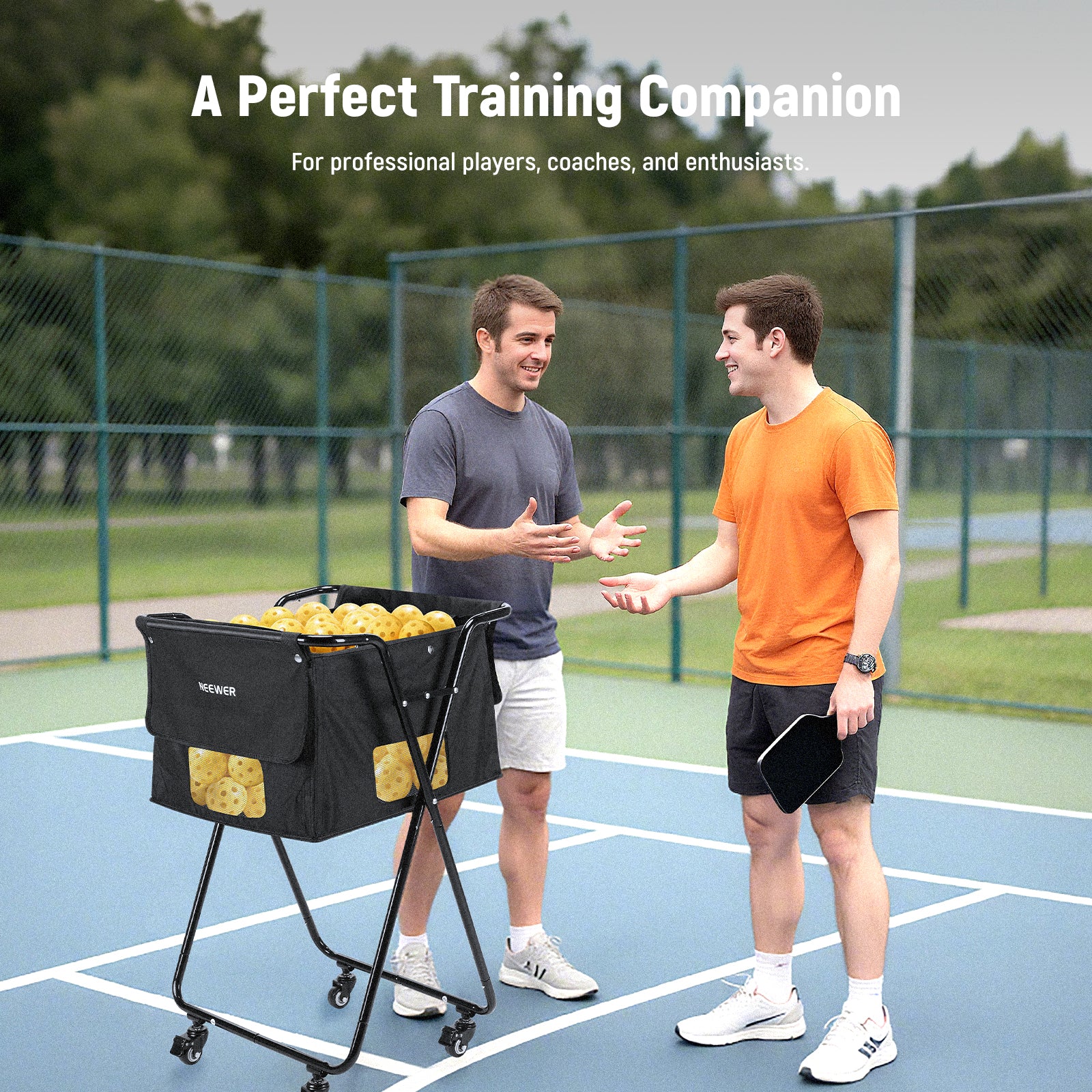 Two boys are using the NEEWER PB01X Tennis Ball Hopper to store tennis balls during practice.